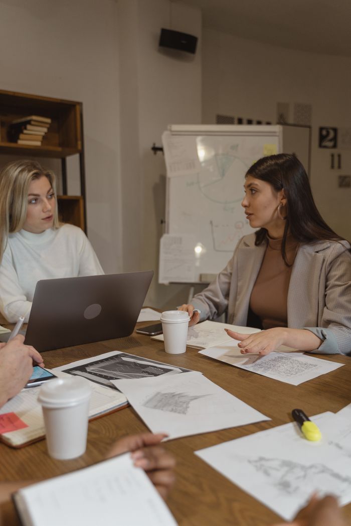 Two women collaborating over documents and coffee in a modern office setting.